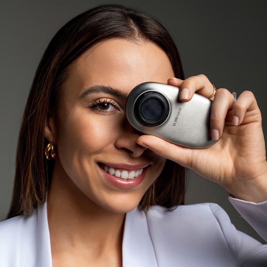Dra. Laura Mombach Mota, dermatologista, com um dermatoscópio junto ao olho